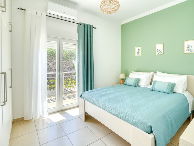 Double bedroom of The Three Sisters House Too with sage wall and balcony doors